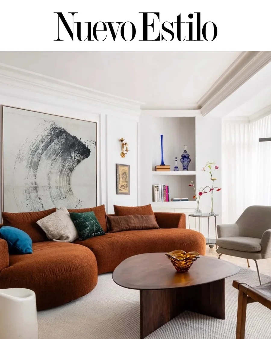 Nuevo Estilo, marzo de 2026: salón con sofá curvo de color teja y obra de arte abstracta, interiorismo de Sandra Vilar
